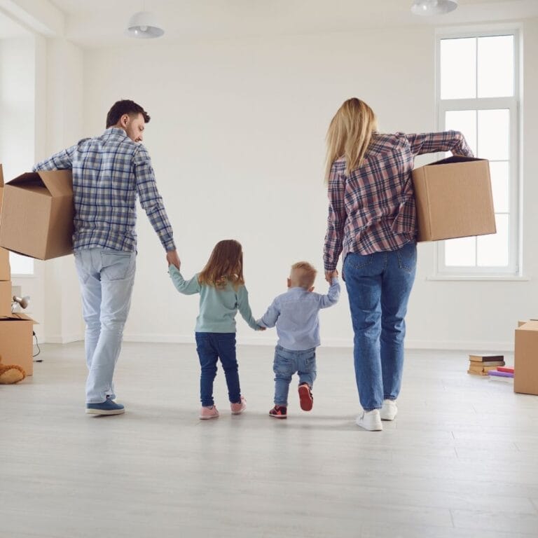 parents holding children's hands walking away in a room that's been packed up