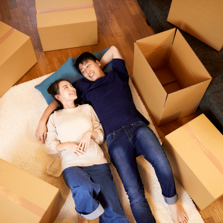 Happy couple laying down in between boxes
